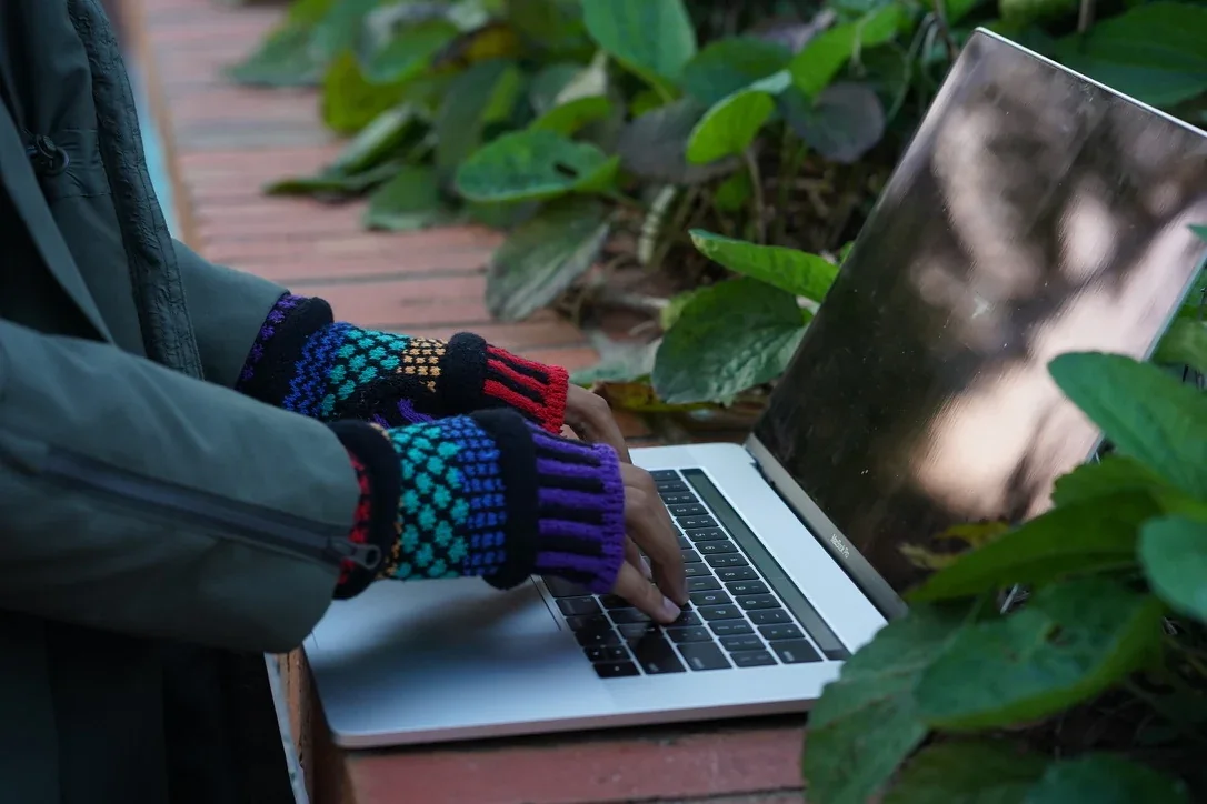 Lifestyle product photography — fingerless gloves at a laptop.