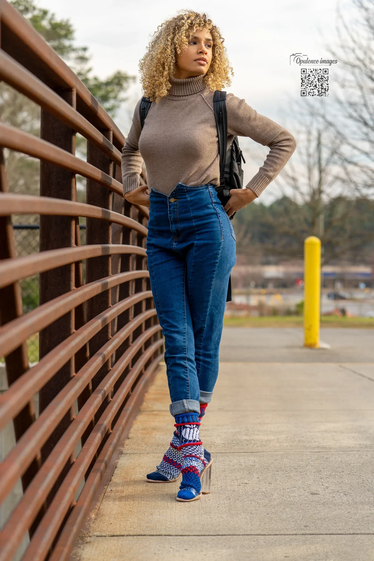 Patterned socks styled with cuffed jeans beside a pedestrian bridge railing.